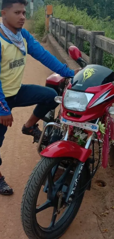 Man posing with red motorcycle on roadside.