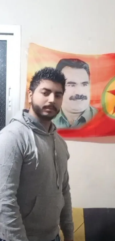 Man standing beside a red flag with a star indoors.