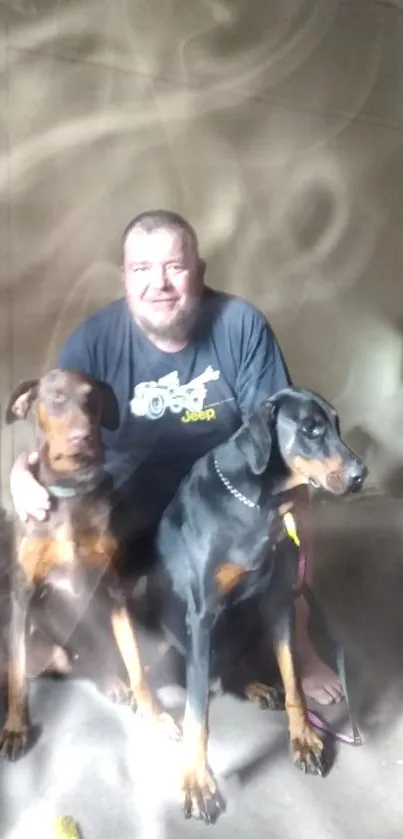 Man sitting with two Dobermans in a softly lit room.