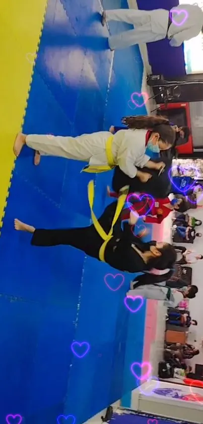 Children practicing martial arts on blue mats with heart overlays.