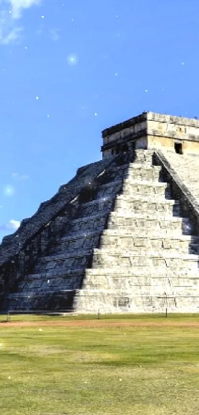 Mayan pyramid under a clear blue sky with grassy foreground.