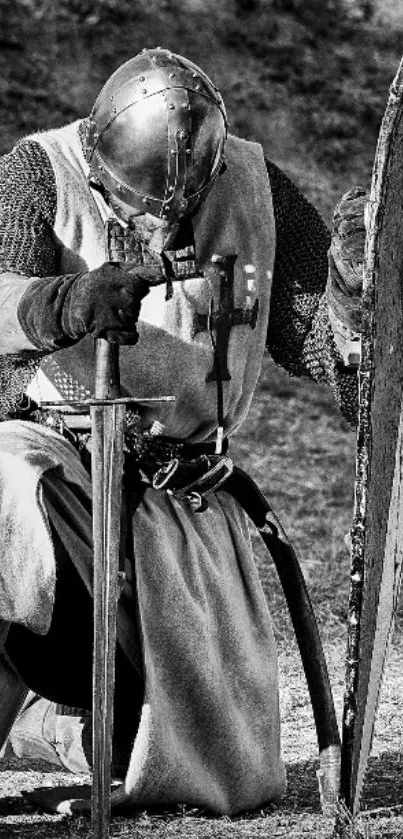 Medieval knight kneeling with a sword and shield in grayscale.