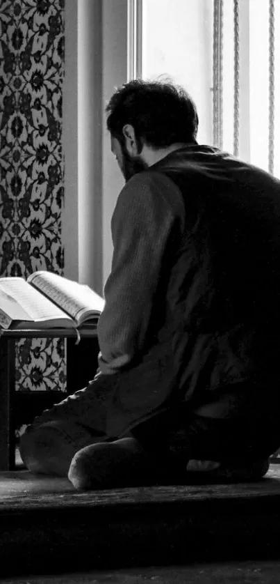 Man meditating by a window in black and white.