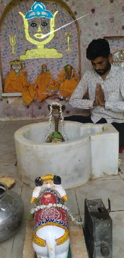 Man praying in Hindu temple with vibrant icons.