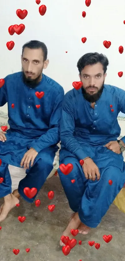 Two men in blue traditional attire sitting indoors.