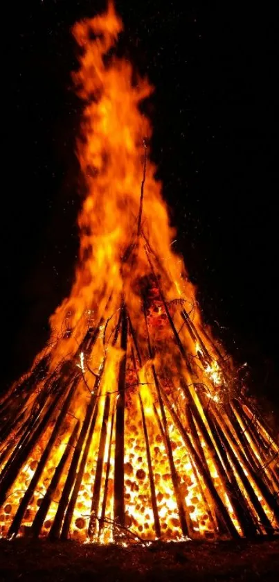 A mesmerizing bonfire with orange flames under a dark night sky.