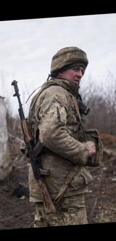 A soldier stands in winter gear in a barren, rural landscape.