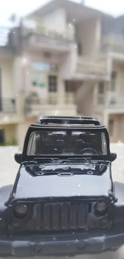 Miniature black Jeep model with blurred urban background.