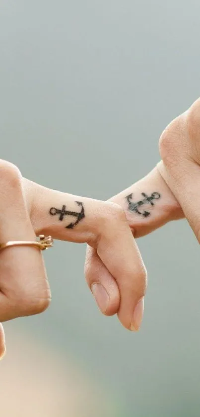 Two fingers with anchor tattoos touching gently.