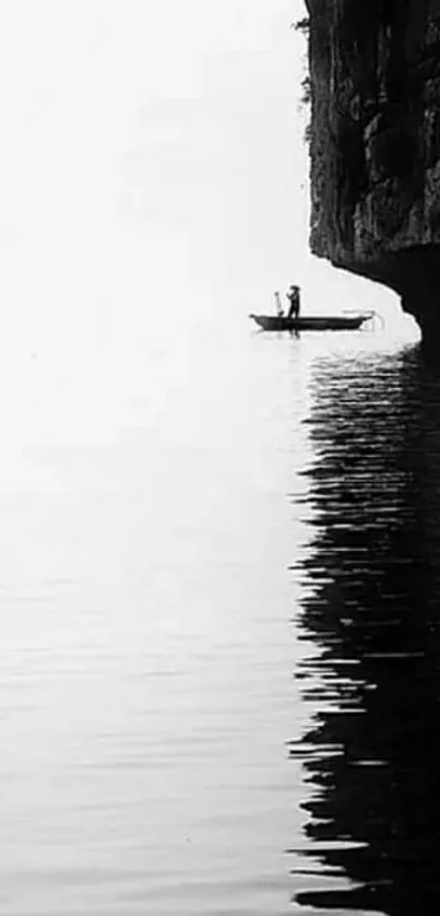 Silhouette of fisherman on boat by a cliff in a minimalist black and white scene.