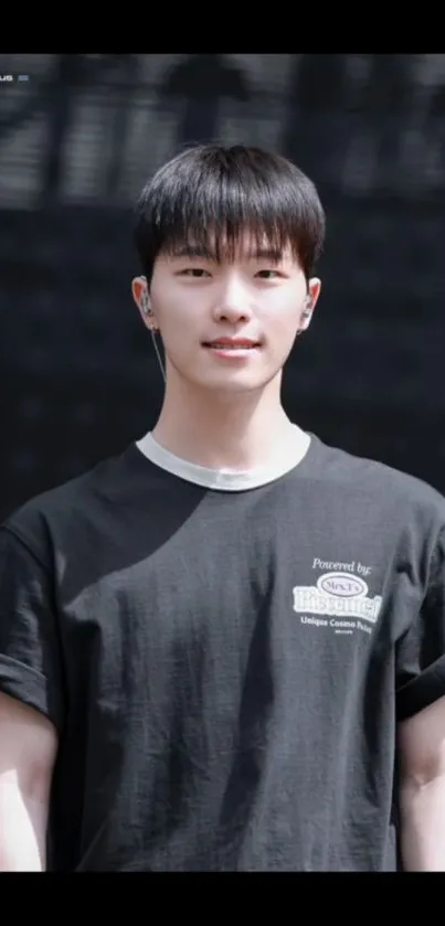 Young person in black T-shirt with a minimalist background.