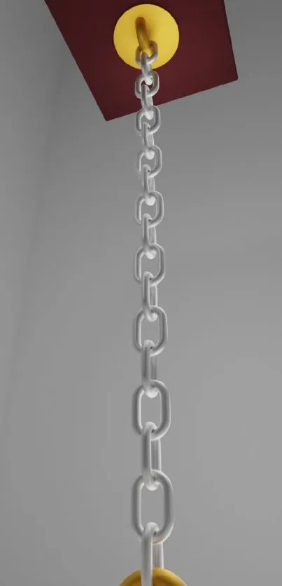 Minimalist metallic chain with a yellow accent against a gray background.