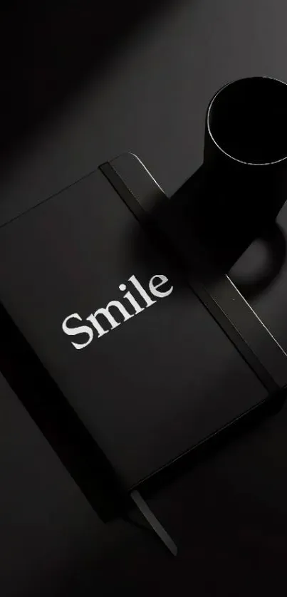 Black notebook with 'Smile' next to a black coffee cup on a dark background.