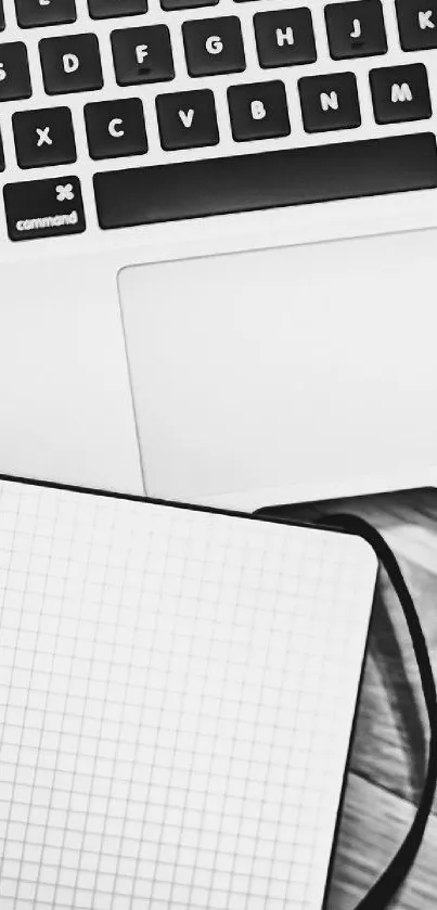 Minimalist black and white desk setup with laptop, notebook, and coffee cup.