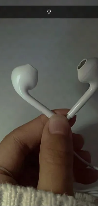 Close-up of white earphones held by hand on a beige background.