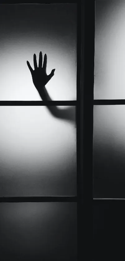 Black and white wallpaper with a hand silhouette on foggy glass.