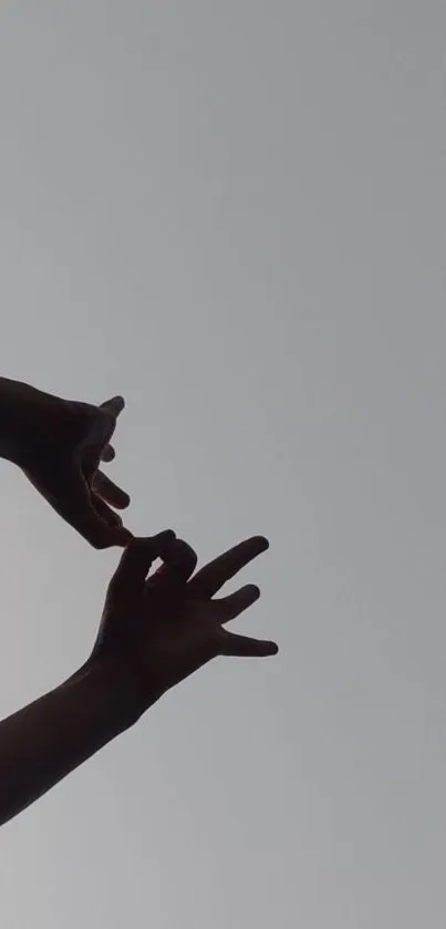 Gray sky with a silhouette of hands, minimalist mobile wallpaper.