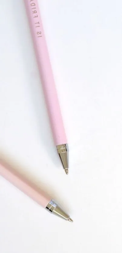 Minimalist design with two pink pens on a white background.