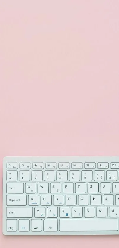 Minimalist pink workspace with keyboard and stationery.