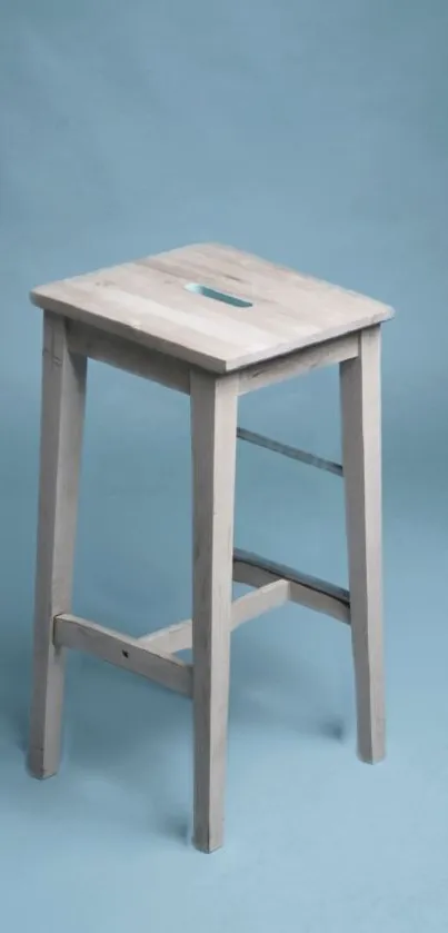 Minimalist wooden stool on pastel blue background.