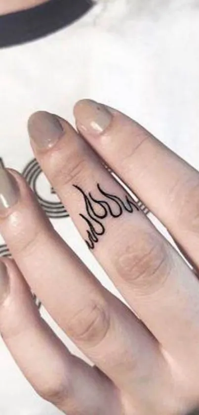 Minimalistic flame tattoo on finger with beige manicure