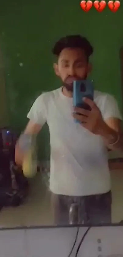 Mirror selfie with man in white shirt and green backdrop.