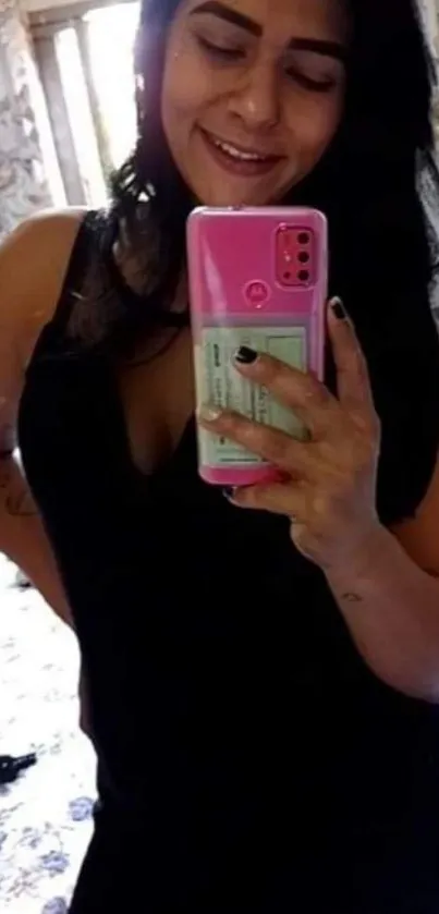 Woman taking mirror selfie with pink phone.