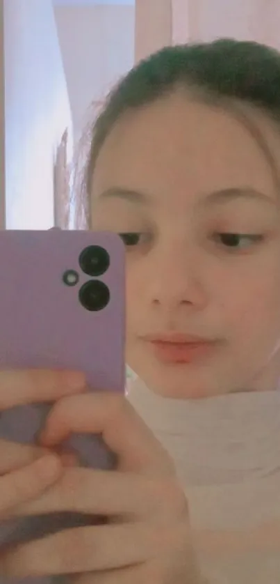 Young person takes a mirror selfie with a purple phone.