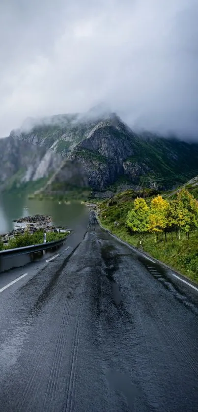 Misty road leading through mountains with lush greenery and cloudy sky.