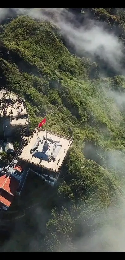 Aerial view of a temple on a misty green mountain.