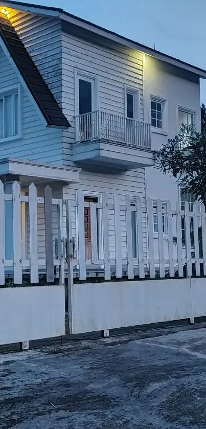 Modern house with white fence at dusk under a blue sky.