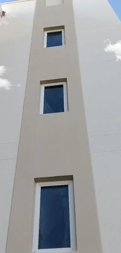 Modern facade with blue windows and clouds in a minimalist design.