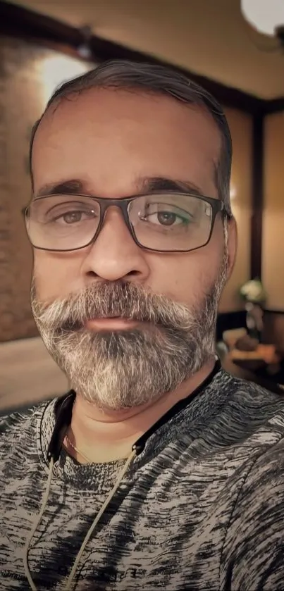 Portrait of a bearded man in a cozy, warmly lit room.