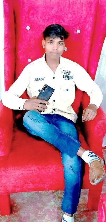 Man sitting in a red chair, holding a phone.