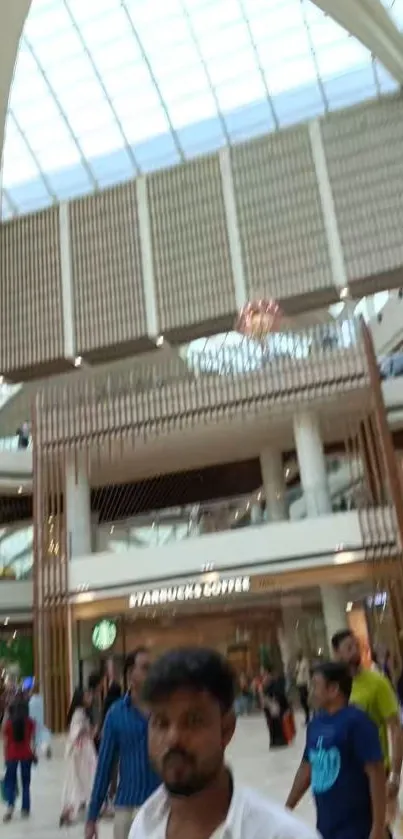 Interior of a bustling shopping mall with shoppers and a glass ceiling.