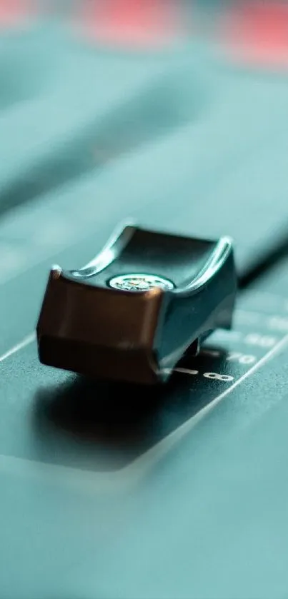 Close-up of sound mixer slider on a teal background.