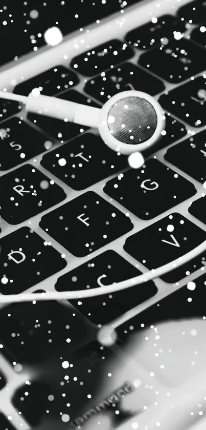 Black and white wallpaper with earbuds on a laptop keyboard.