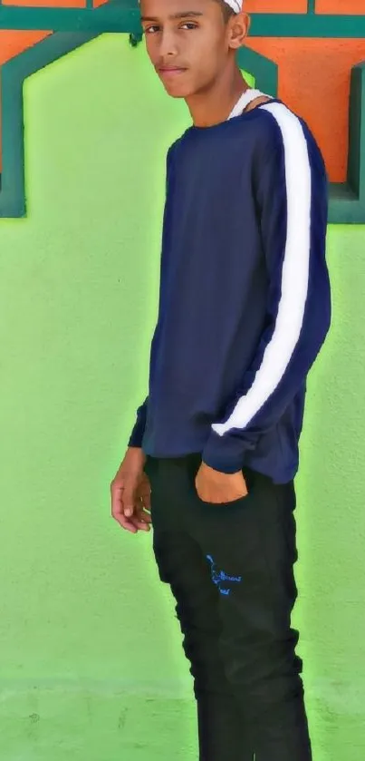 Portrait of a young person in blue attire against a green wall.