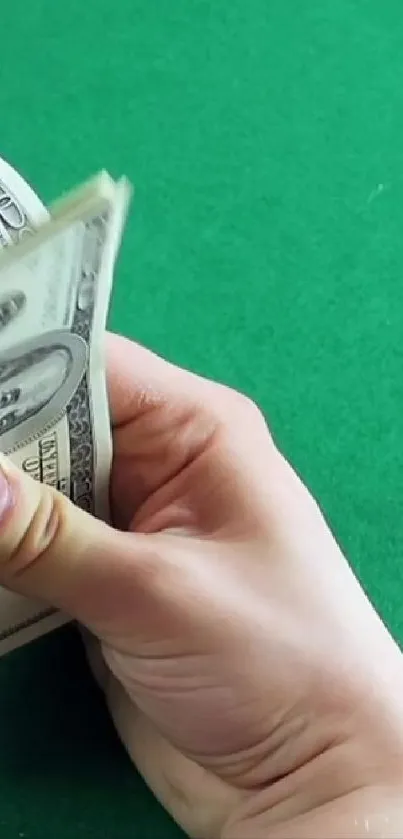 Hands counting dollar bills on a vibrant green surface.