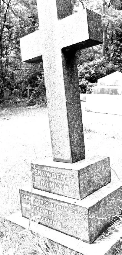 Monochrome cemetery cross amidst trees and graves.