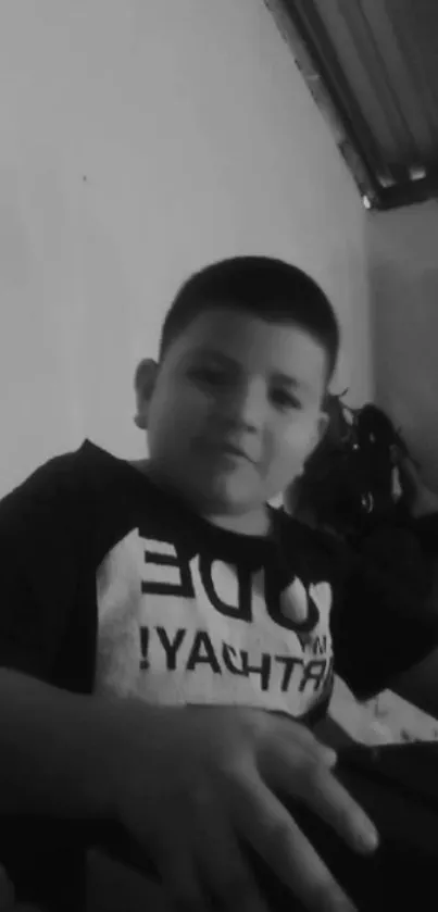 Monochrome image of a young boy sitting.