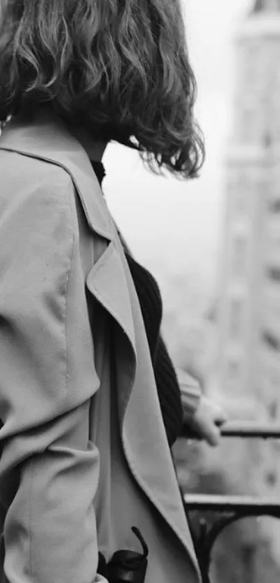 Monochrome photo of a person in a trench coat overlooking a cityscape.