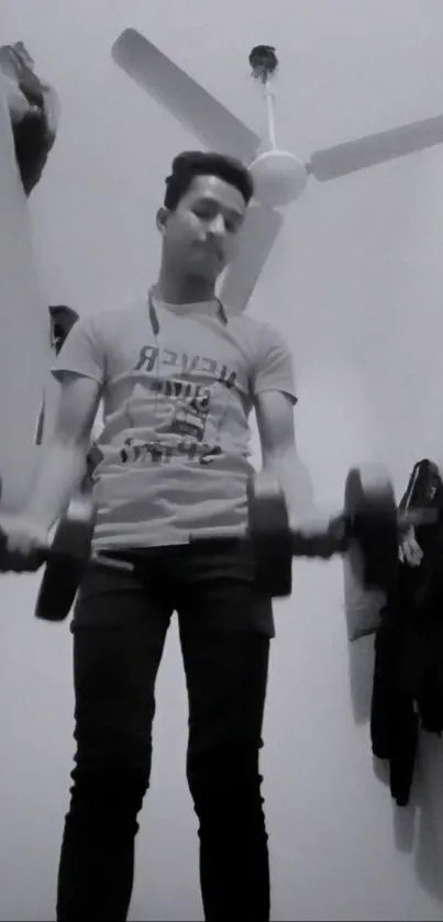 Monochrome image of a person lifting weights indoors.