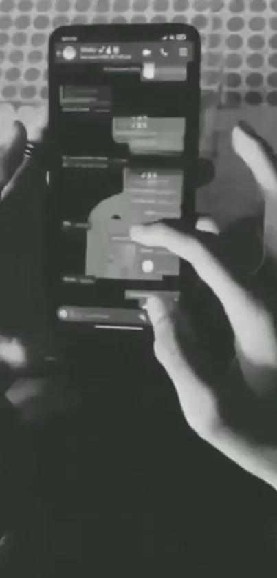 Black and white image of hands operating a smartphone with visible interface.