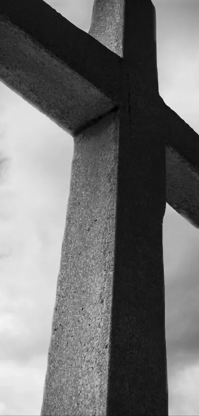 Monochrome stone cross against a cloudy sky, exemplifying serenity.