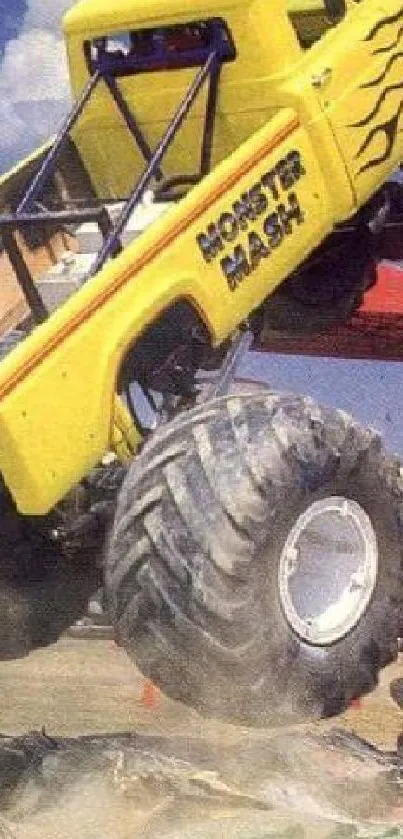 Yellow monster truck jumps over obstacles in a high-energy action shot.