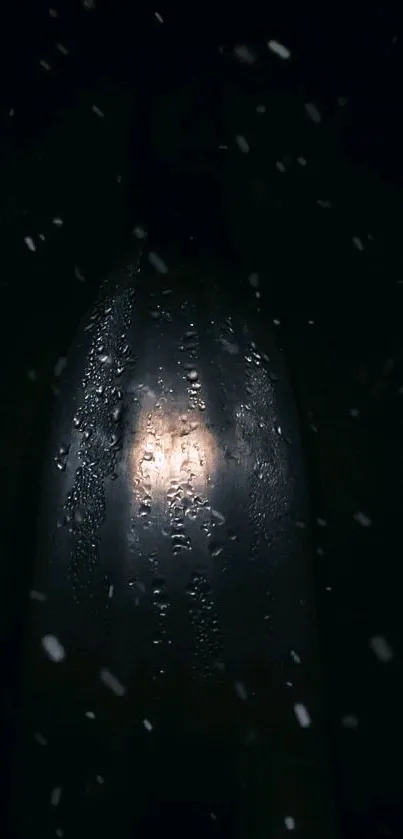 Moody bottle with spotlight and droplets on dark background.