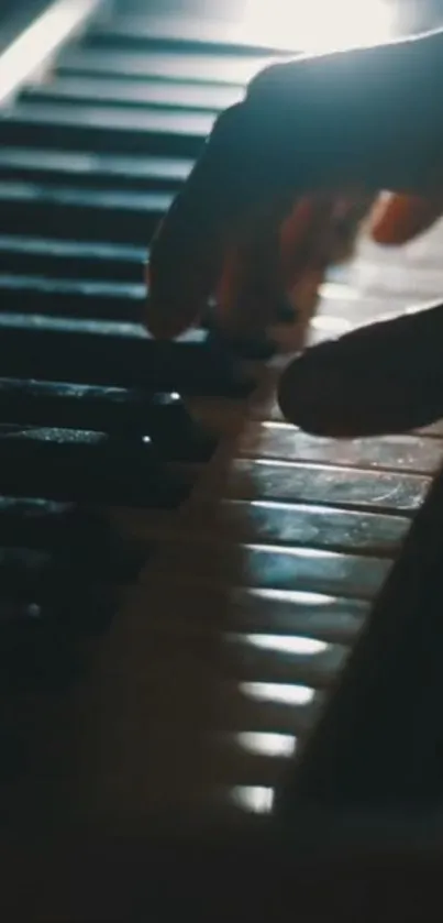 Hand playing piano keys in dark moody light.