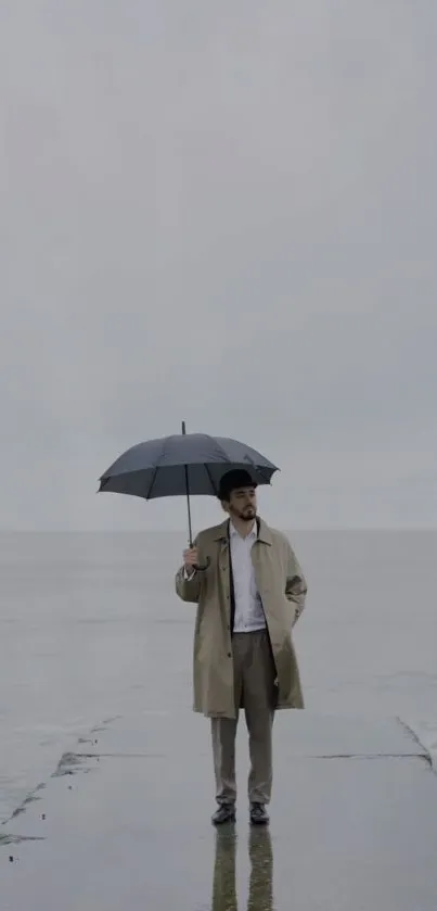 Person with umbrella at grey seaside on a calm, moody day.