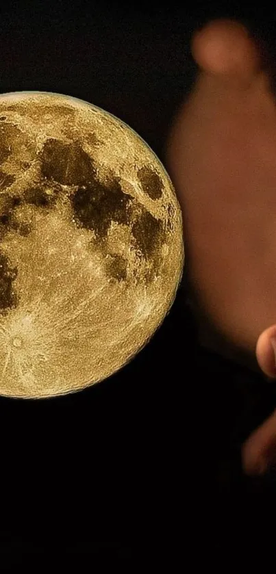 Hand holding a glowing full moon against a dark backdrop.